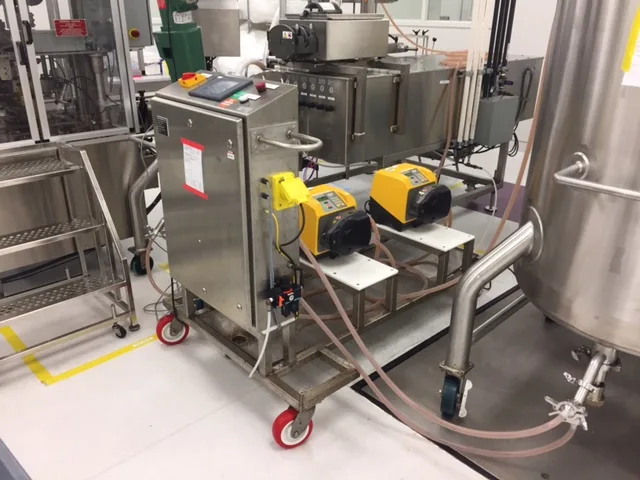 Custom fill and transfer skid with two peristaltic pumps beside a stainless steel process vessel
